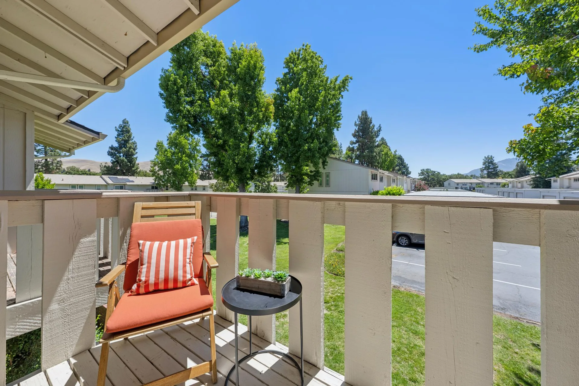 Second-story balcony overlooking community parking area with blue sky