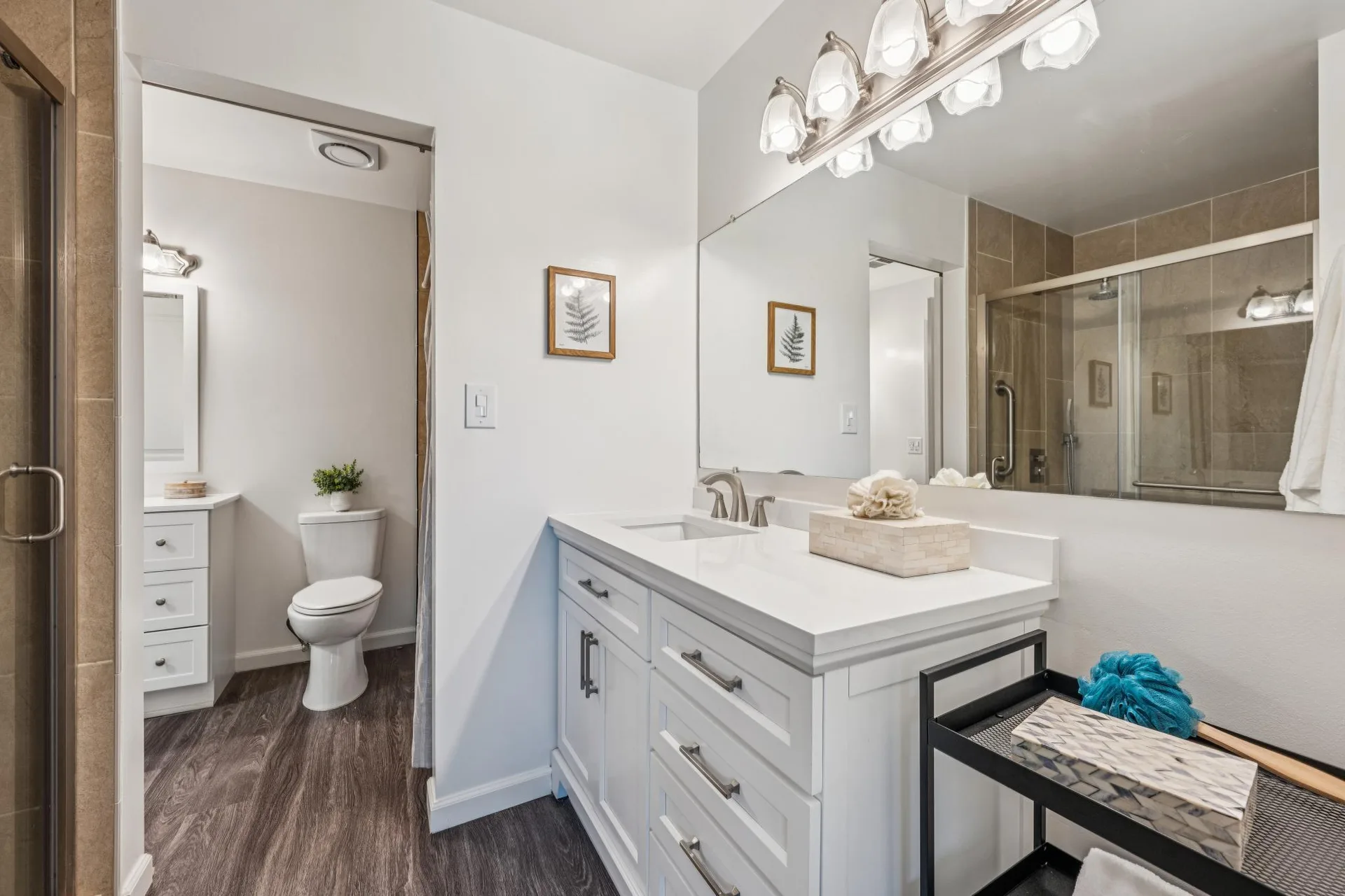 Full bathroom with white shaker vanity, quartz countertops, and wood-vinyl flooring