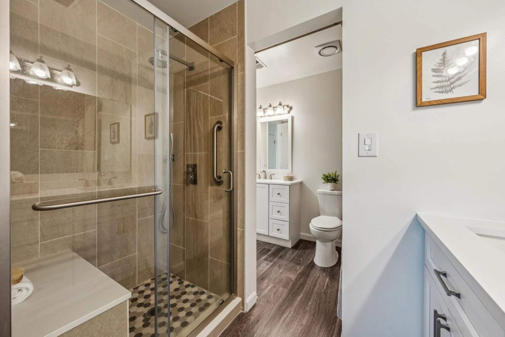 Bathroom showing tile shower with hex floor and white vanity with quartz counters