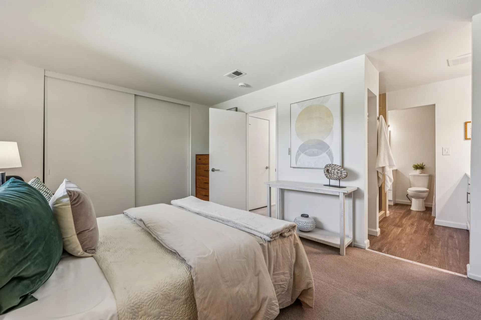Bedroom with bed, tall dresser, console table, and decorative wall art