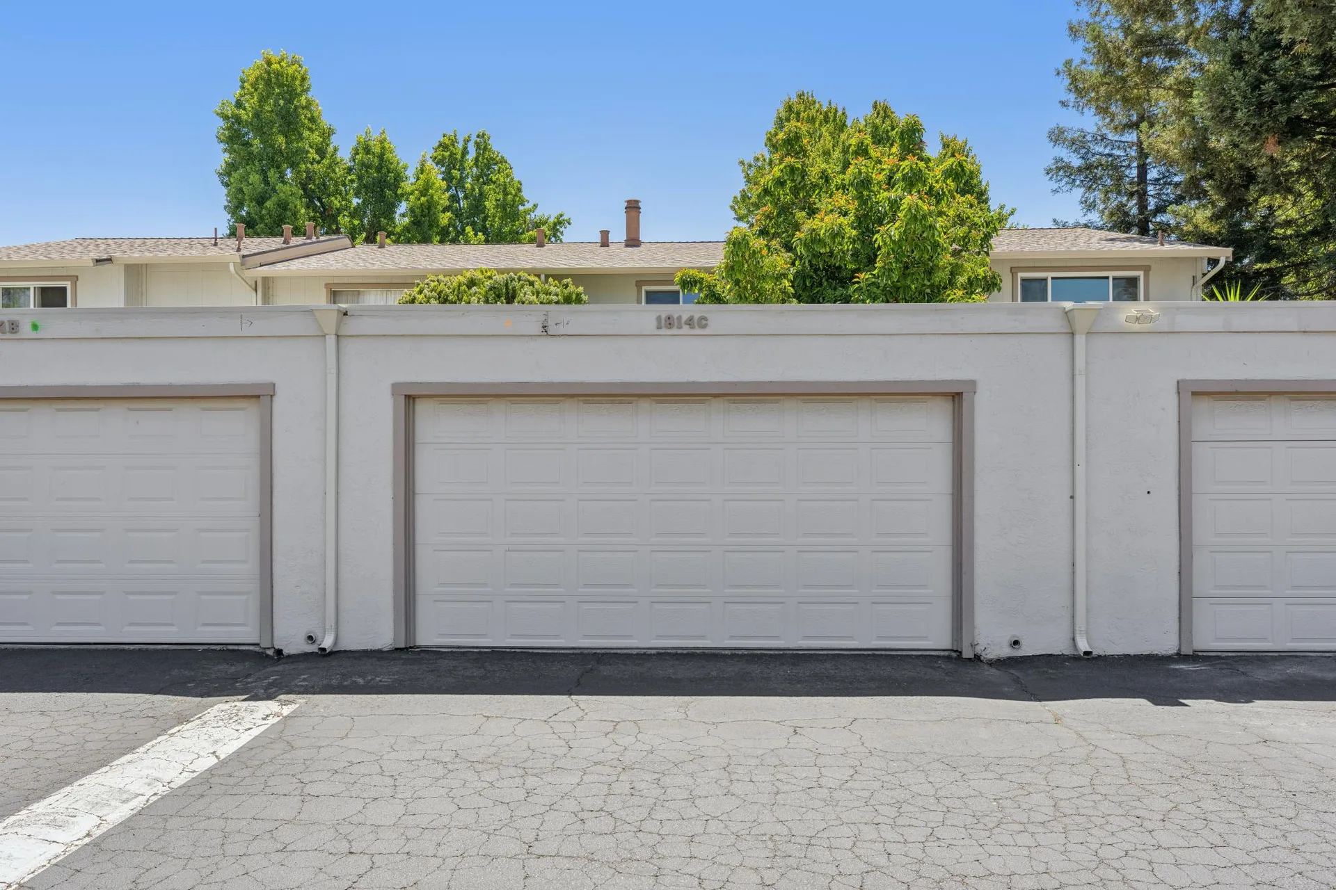 Row of detached townhome garages with stucco walls and asphalt driveway