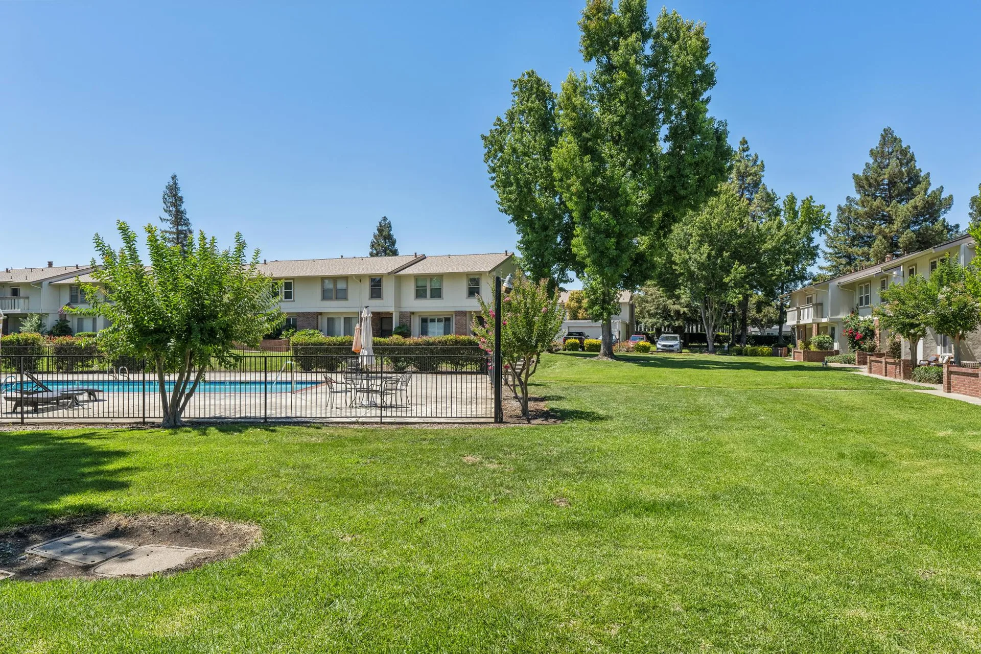 Community pool and common area with stucco buildings and blue sky