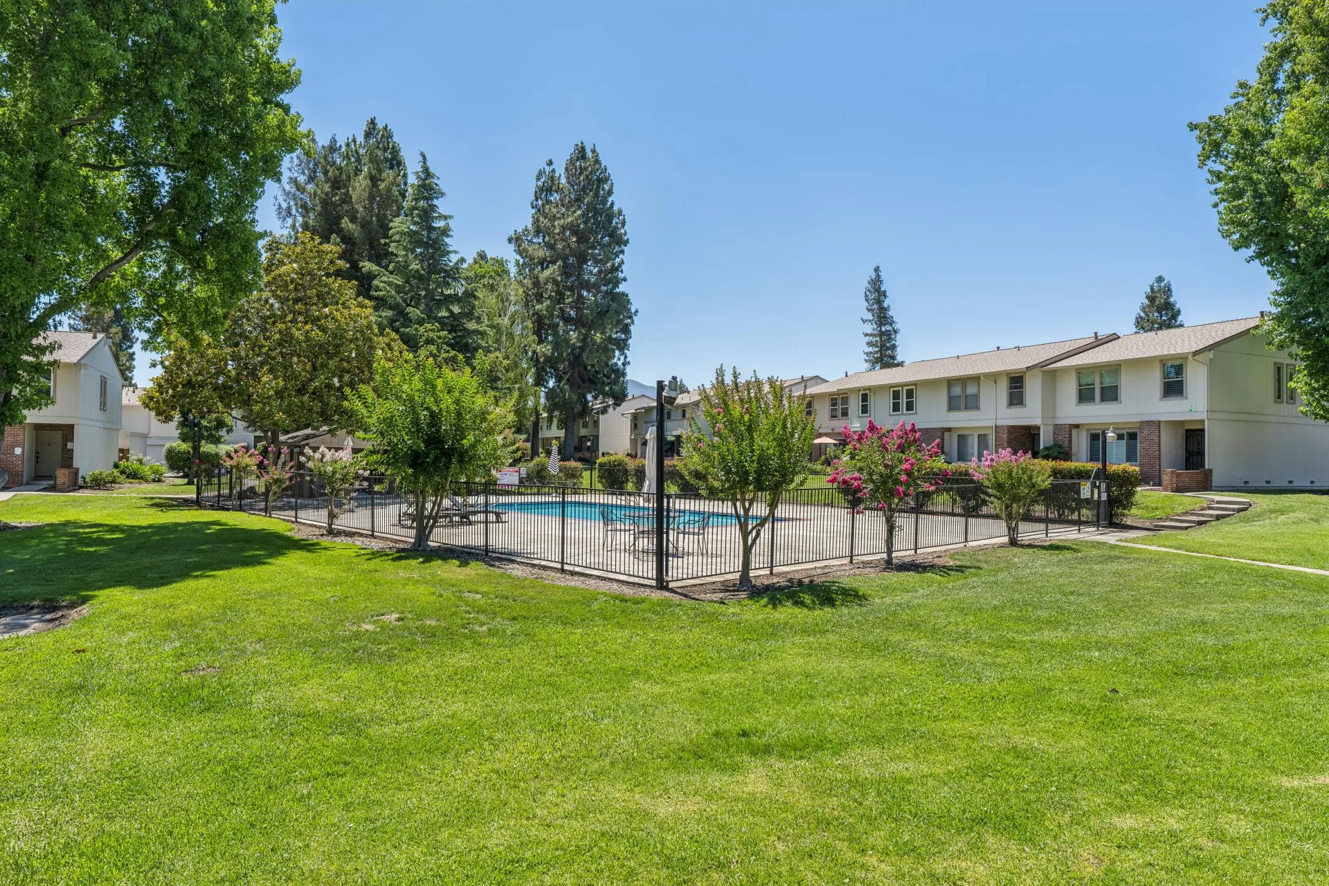 Community swimming pool with cream siding buildings and mature landscaping