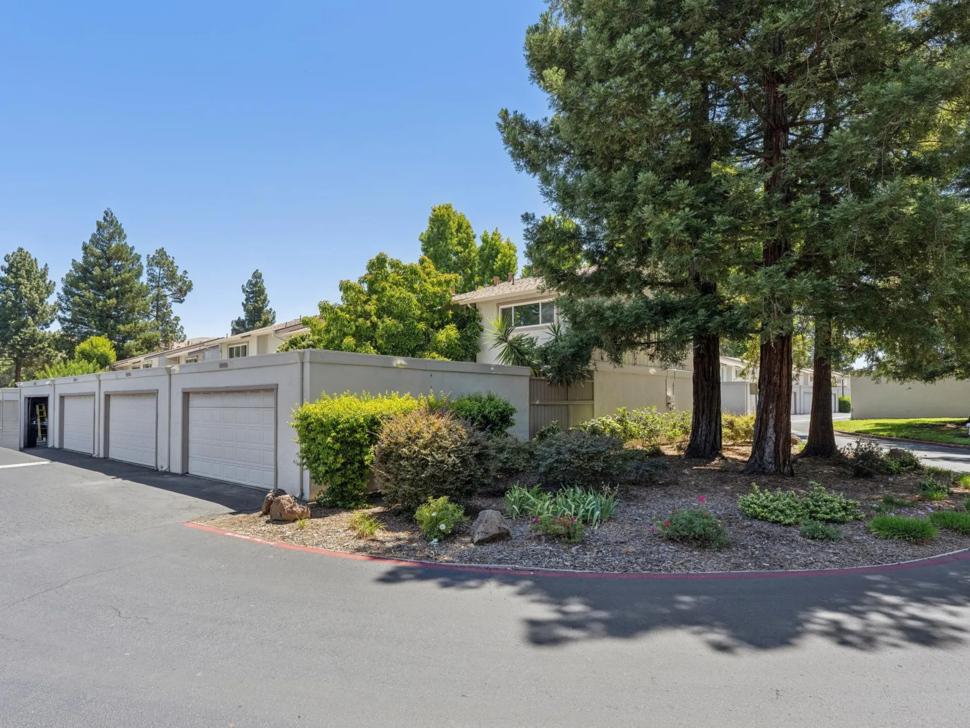Community garages with landscaping and mature trees along the driveway