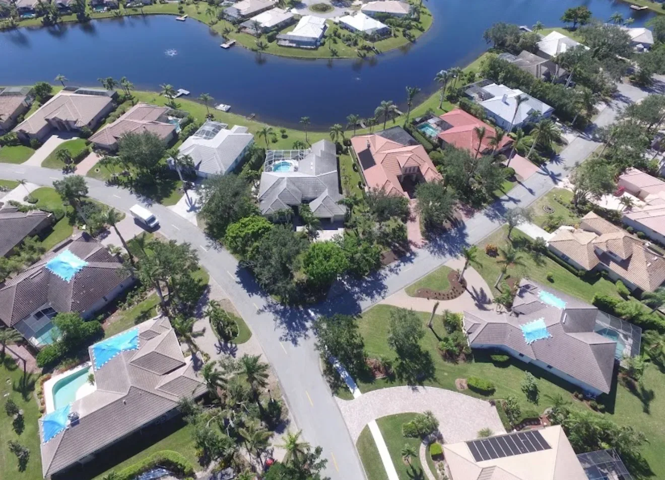 Aerial drone photograph of the Longshore Lake subdivision in North Naples, Florida, showing the gated community layout, homes, and surrounding landscape from above