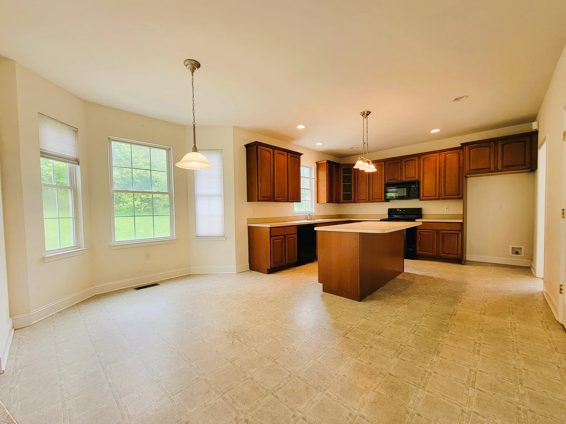 Kitchen island with wood cabinets and bay windows