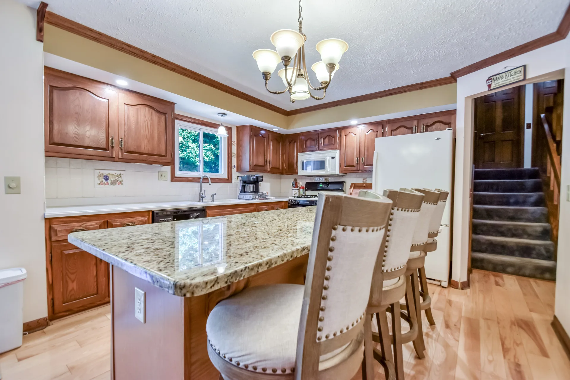 Kitchen with granite island seating, oak cabinetry, and hardwood floors