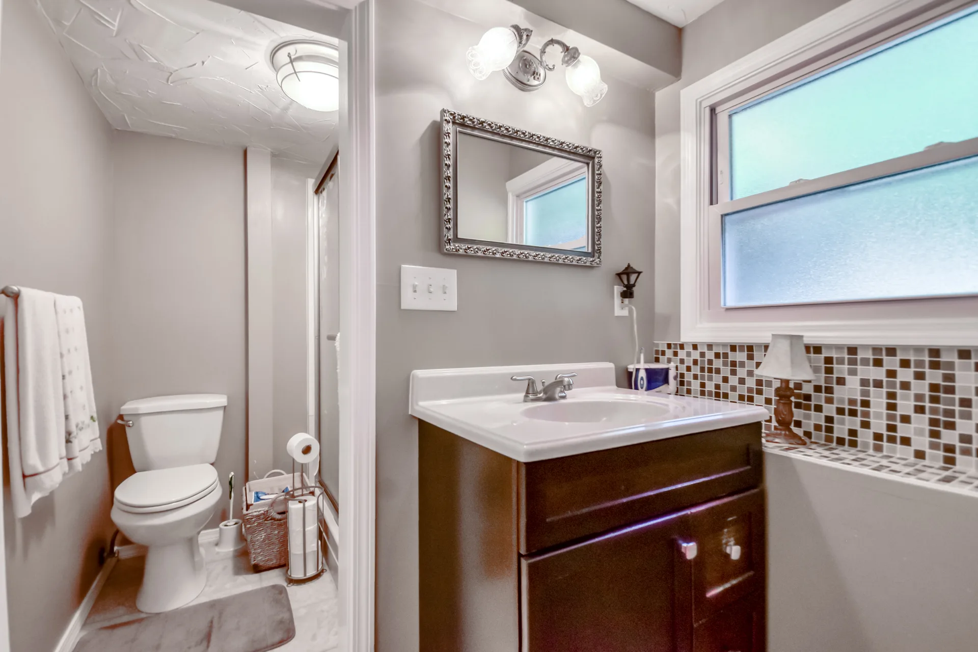 Bathroom with dark wood vanity and mosaic tile backsplash