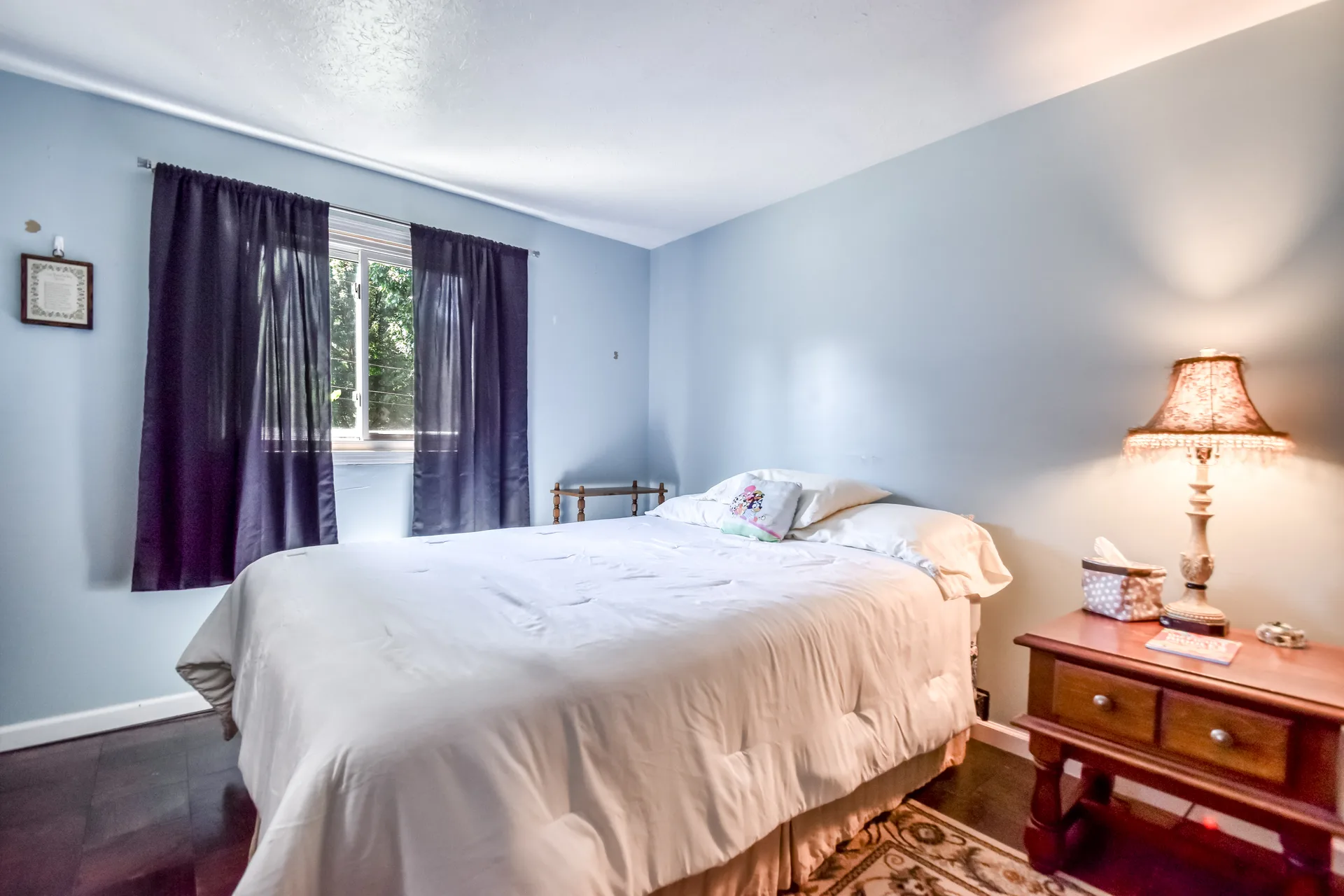 Bedroom with light blue walls and dark hardwood floors