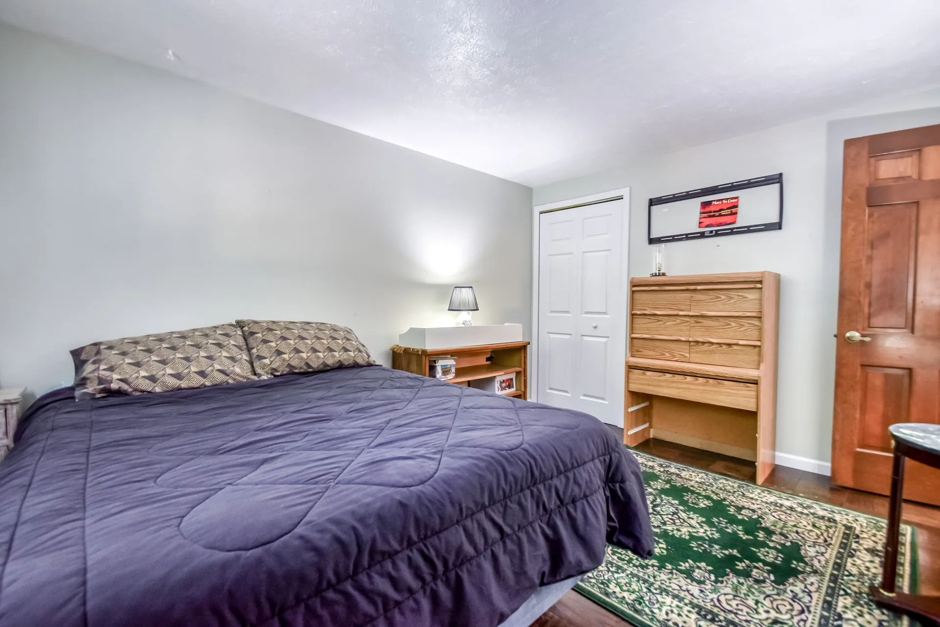 Bedroom with dark quilt and wooden dresser