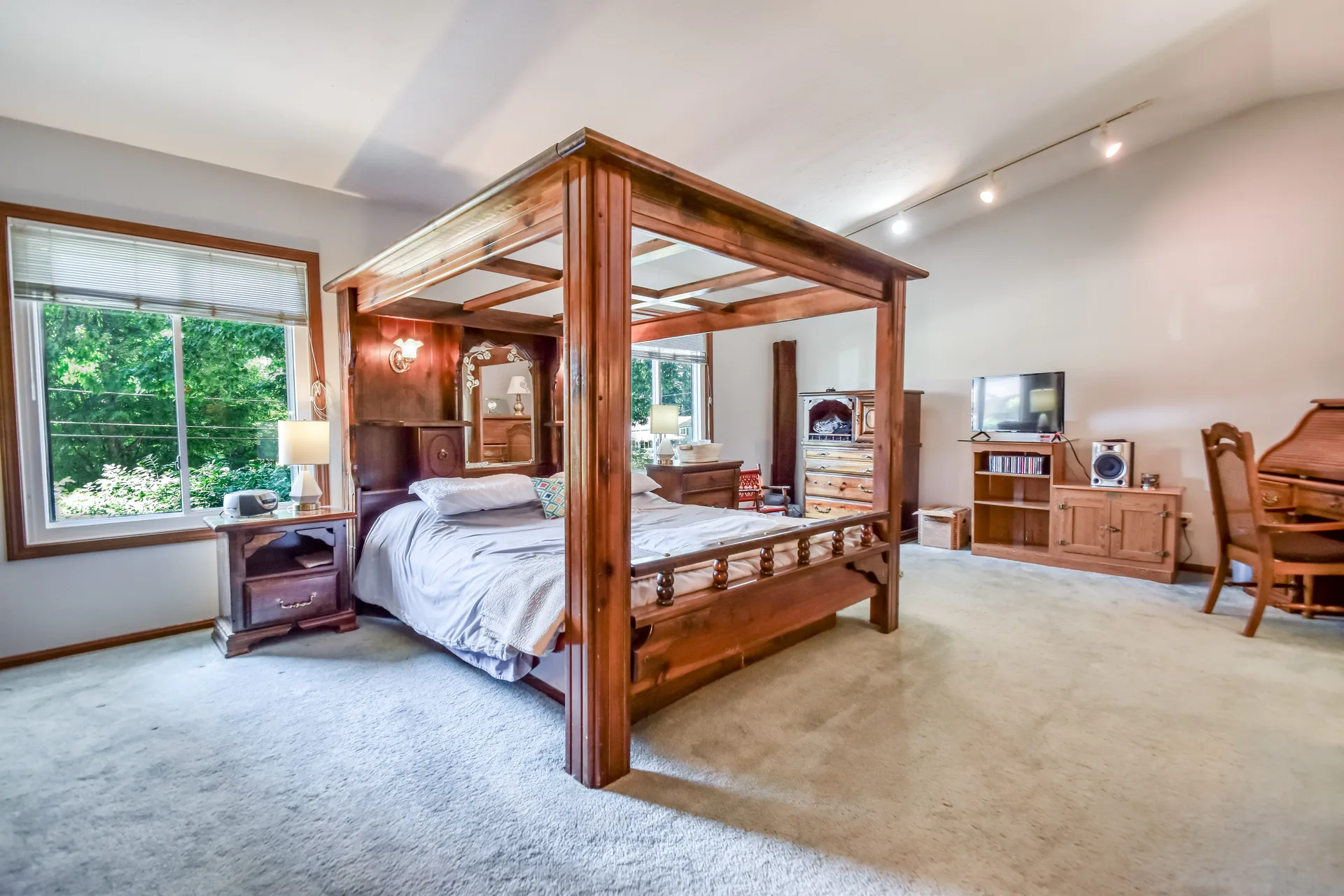 Primary bedroom with four-poster bed and multiple windows