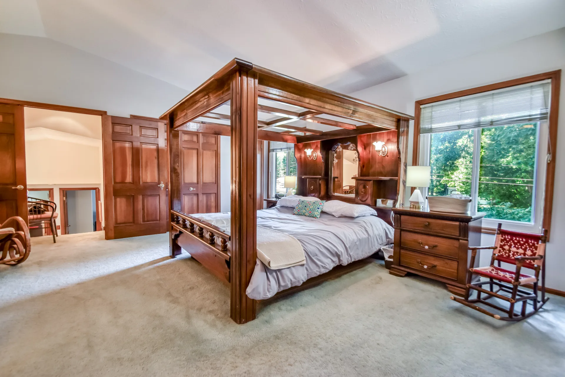Master bedroom with wooden canopy bed and natural daylight