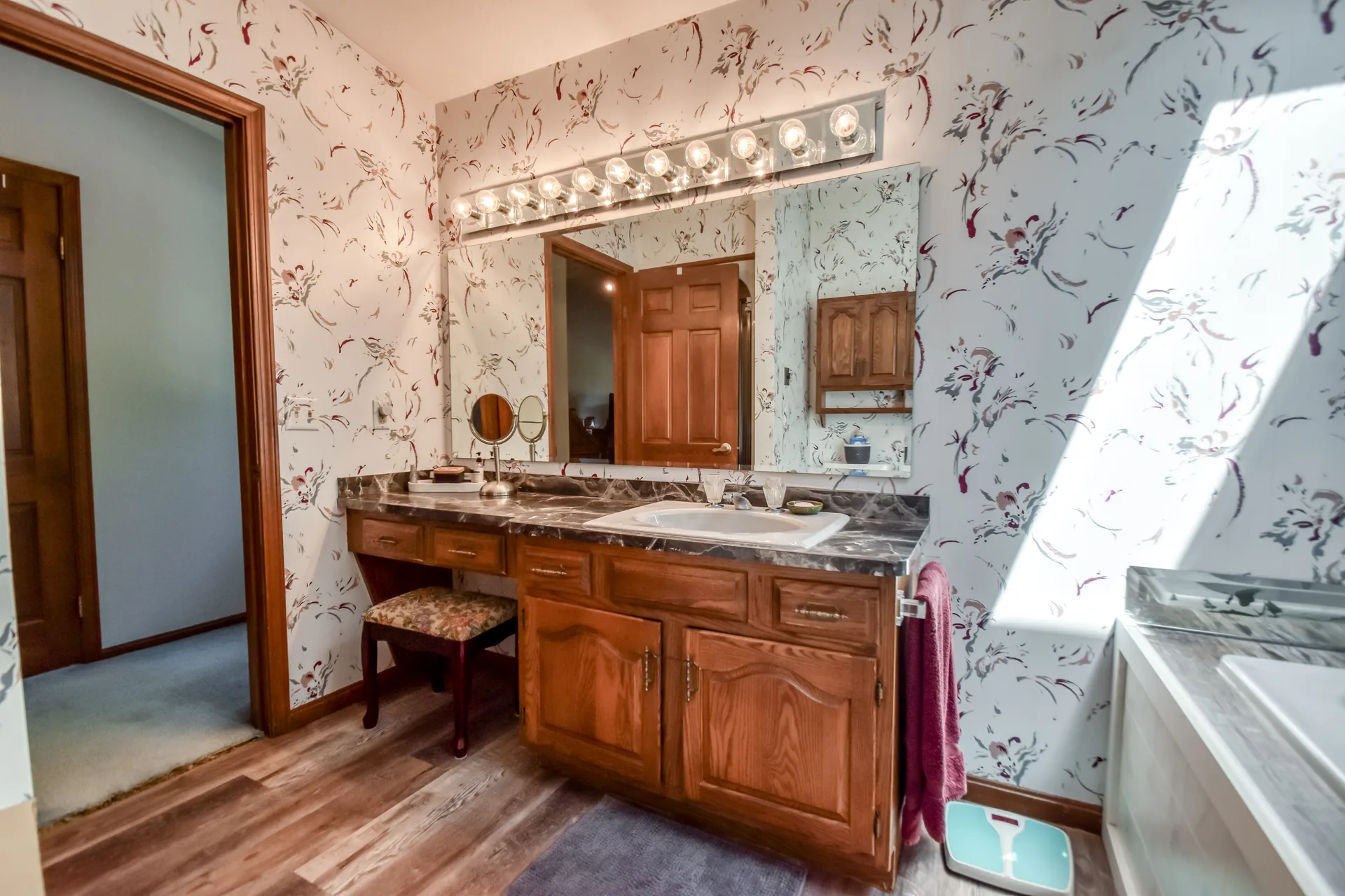 Master bathroom vanity area with patterned wallpaper
