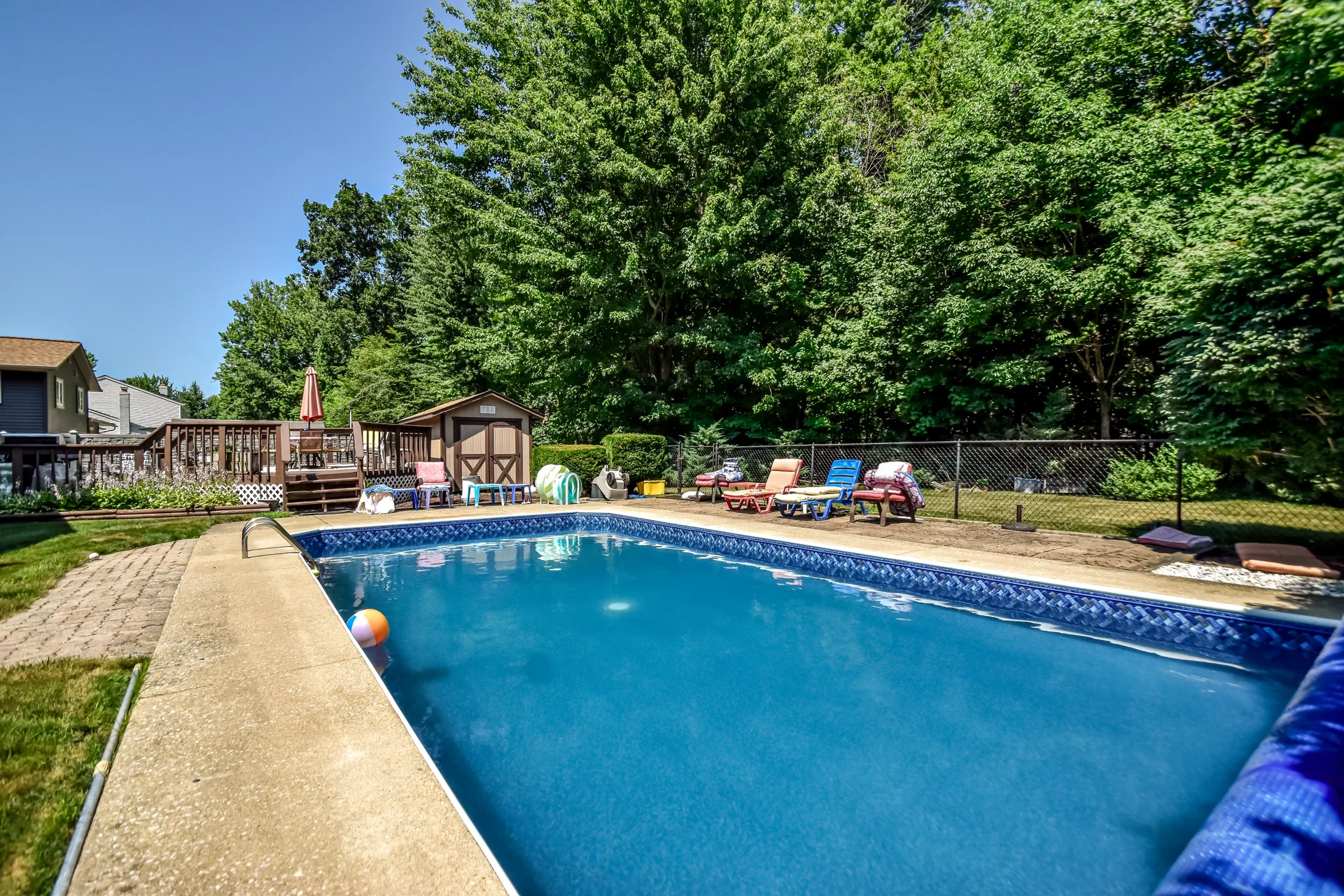 In-ground pool with sun deck and surrounding trees