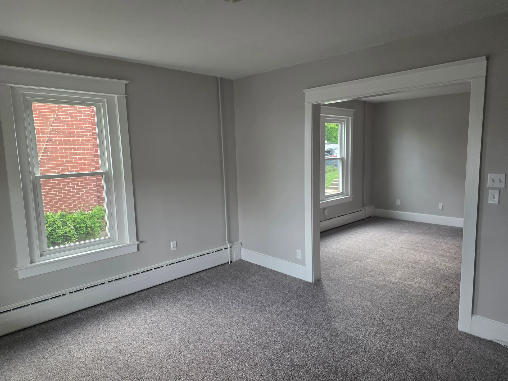 Living and dining room with crown moulding, fresh grey paint, and new carpeting