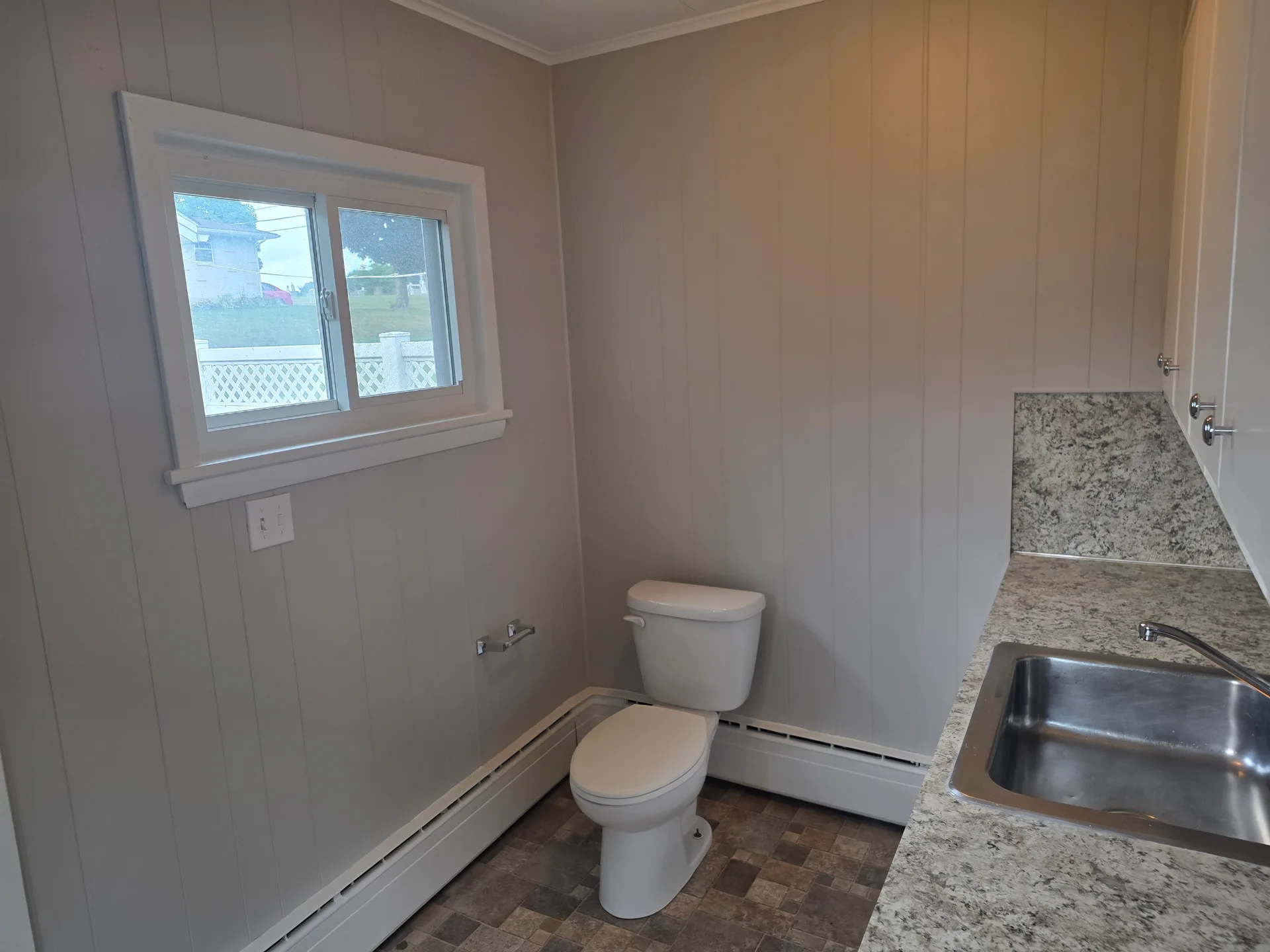 Half bathroom with grey paneled walls and stone-look countertop