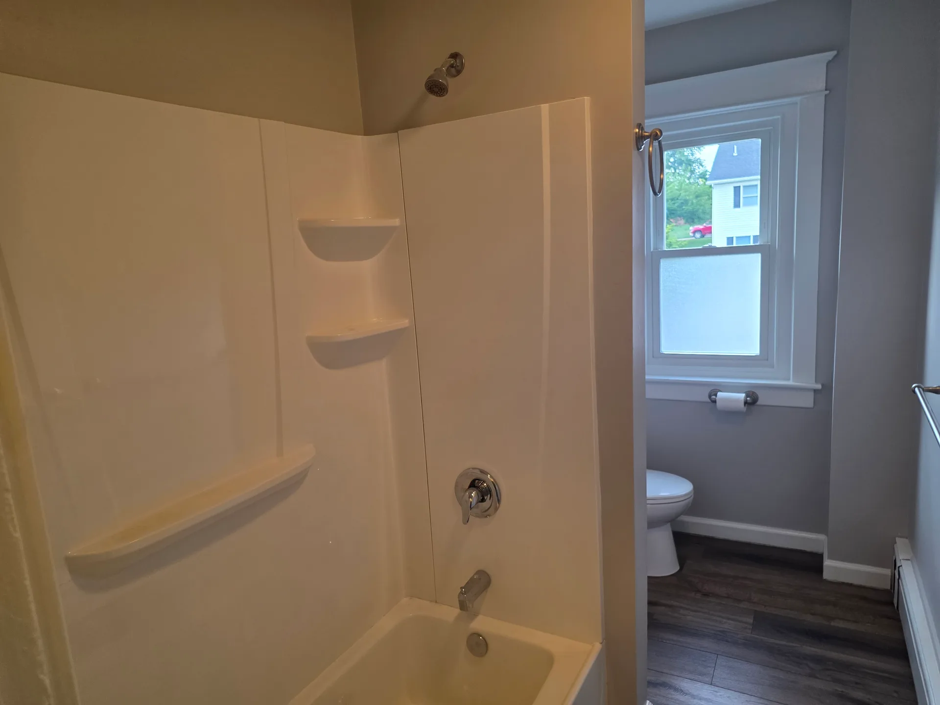 Full bathroom with shower-tub combo and wood-look flooring
