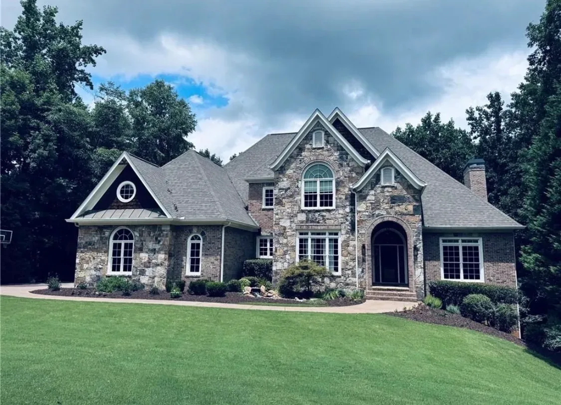 2140 Tee Dr, a luxury estate in the Executive Estates section of Chateau Elan, Braselton Georgia, with stone facade, landscaped front yard, curved walkway, and mature trees