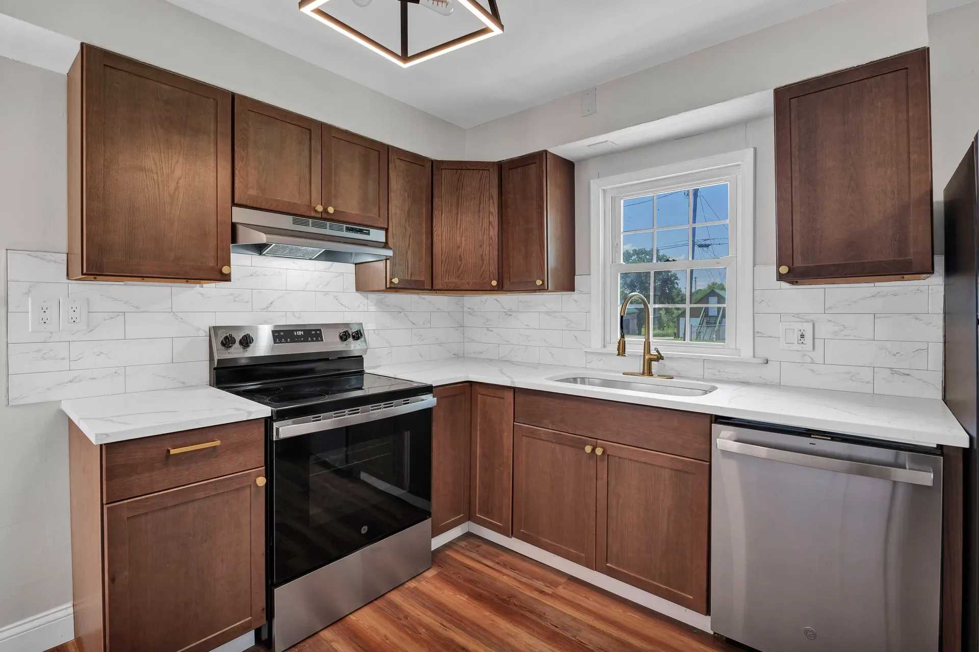 Modern ranch kitchen with dark stained wood cabinetry, white quartz countertops, brass hardware, and stainless steel appliances
