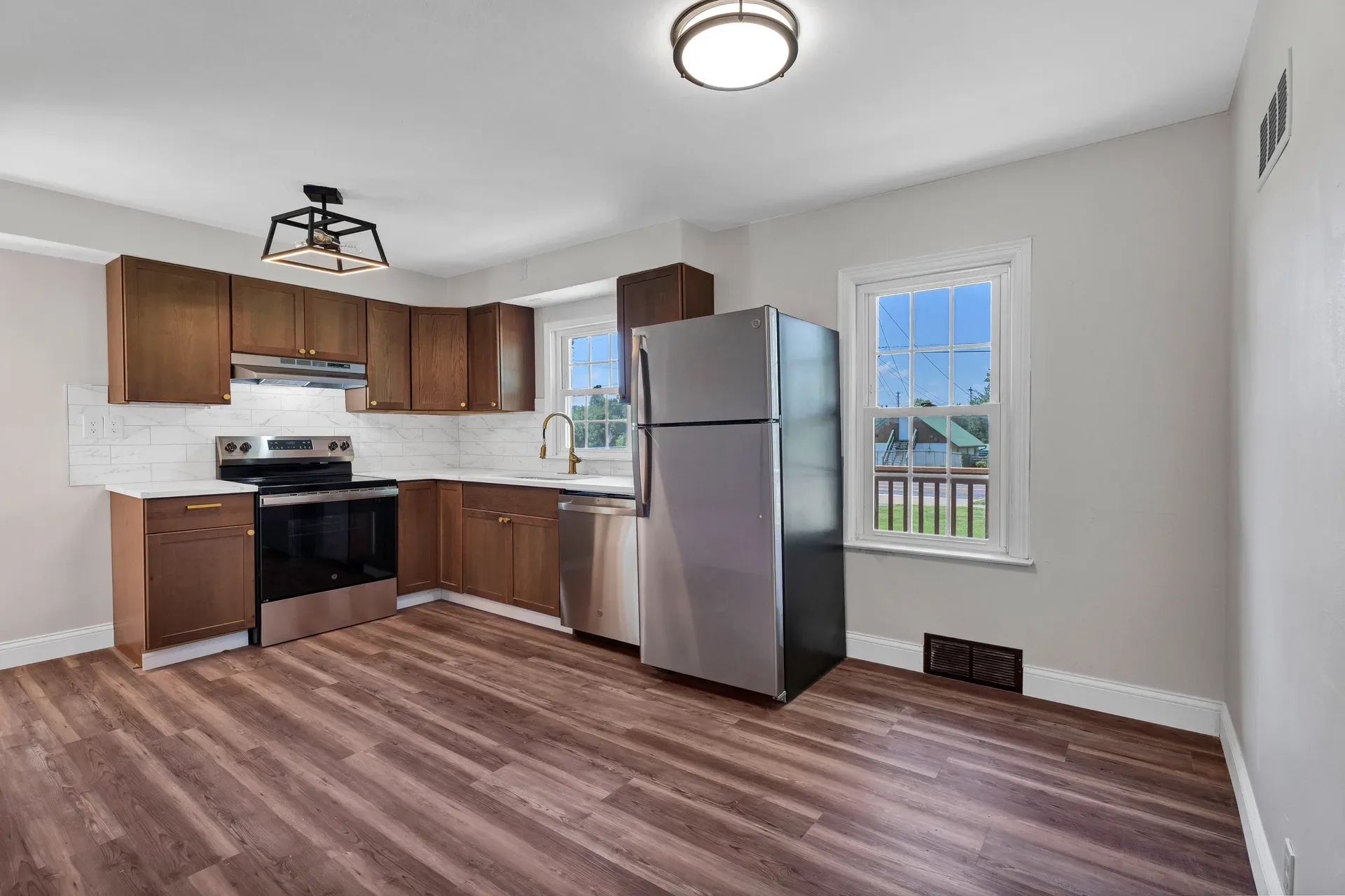 Kitchen and breakfast room with wood-finished cabinetry, white quartz countertops, subway tile backsplash, and stainless steel appliances