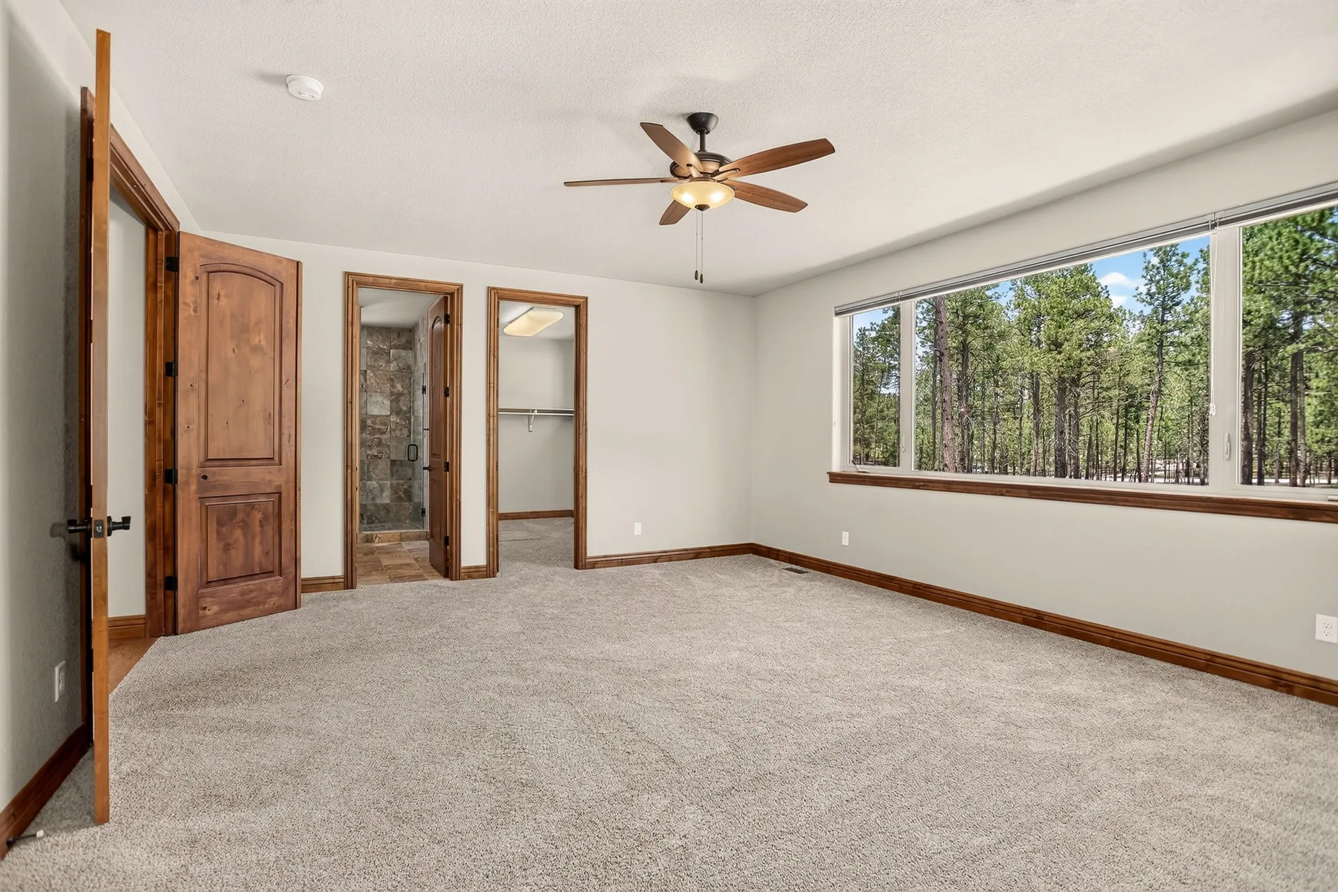Master bedroom with forest view and carpeted floors