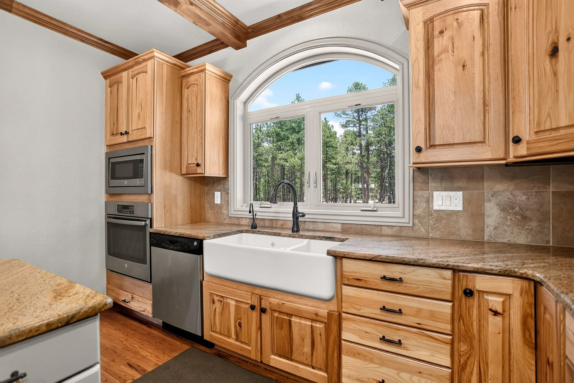 Kitchen sink area with farmhouse sink and arched window