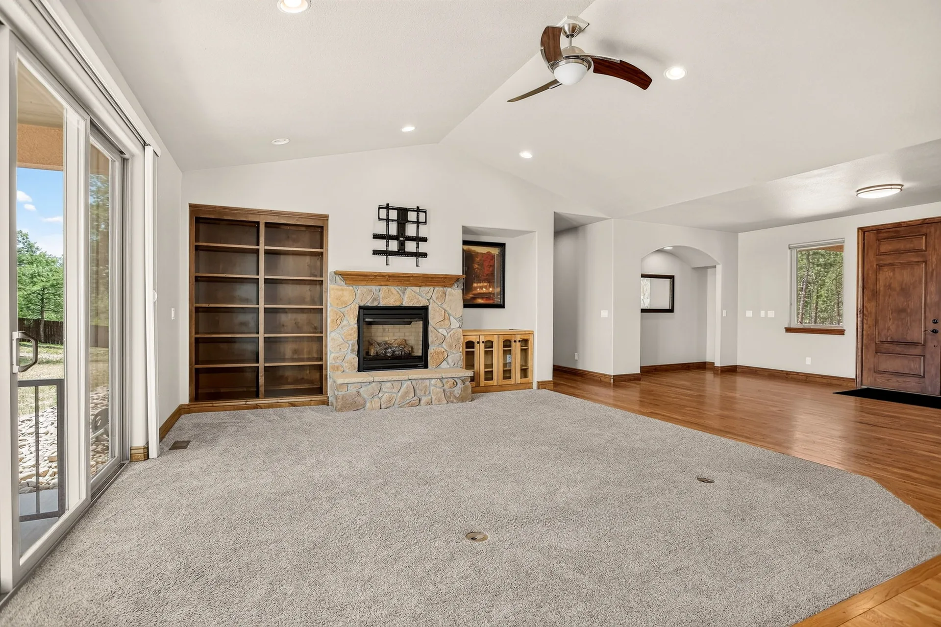 Great room with stone fireplace, vaulted ceilings, and built-in wooden shelving
