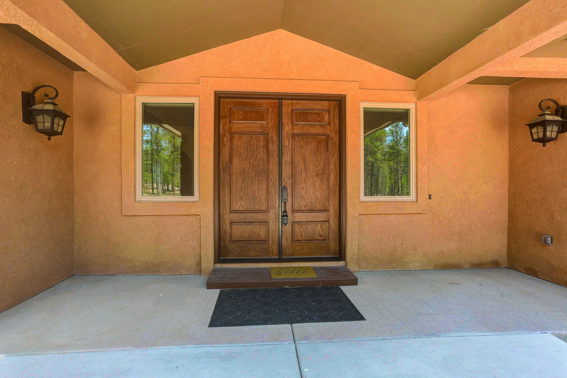 Front entryway with double wood doors and stucco exterior
