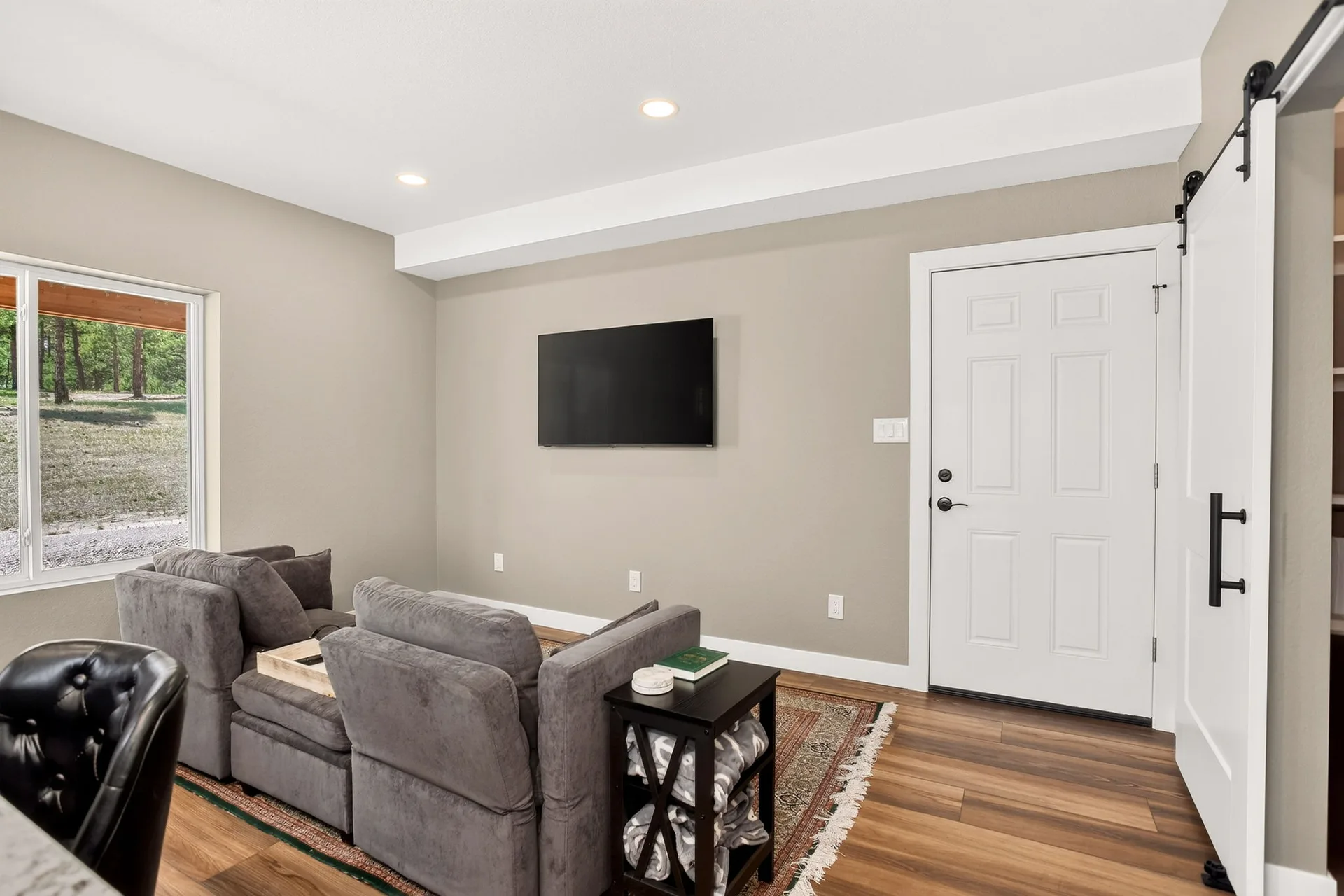 Furnished apartment living room with a sectional sofa, mounted TV, and white sliding barn door