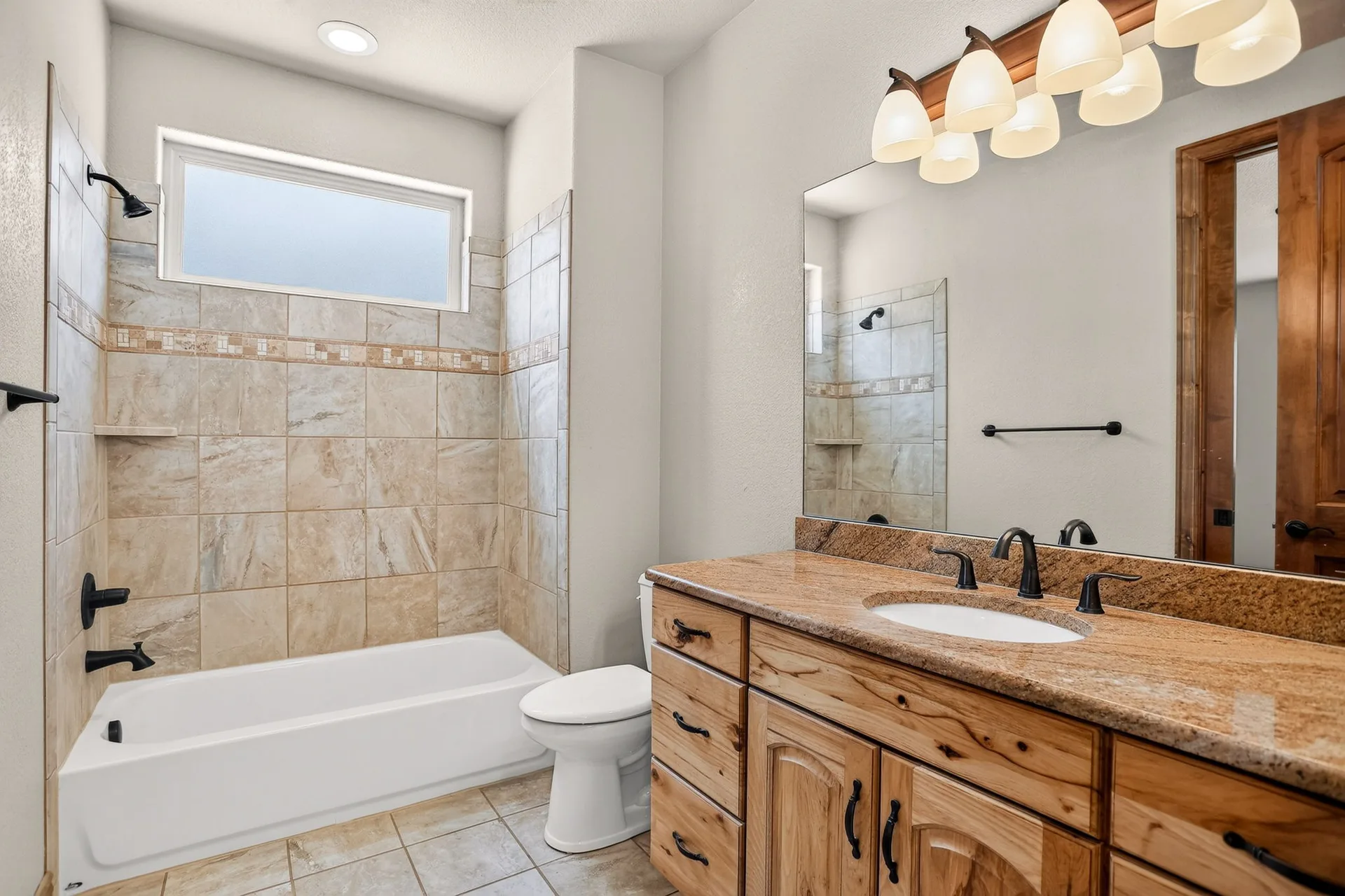 Bathroom with wood vanity, mosaic tile, and five-light fixture