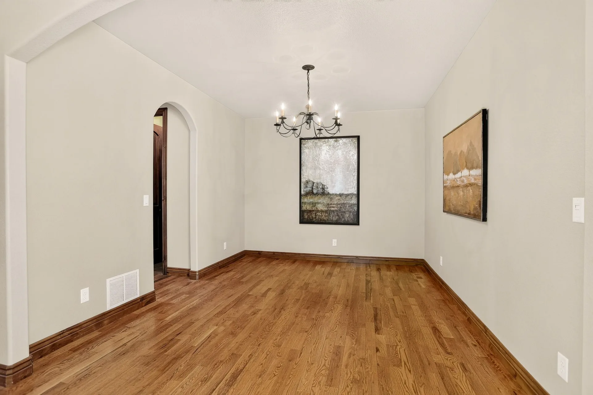 Dining room with hardwood floors, a hanging chandelier, and framed wall art
