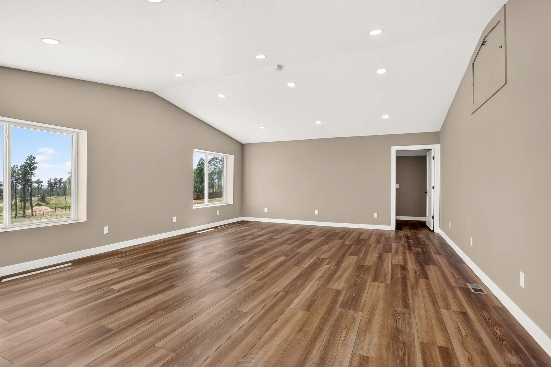 Vaulted living room with plank flooring and recessed lighting