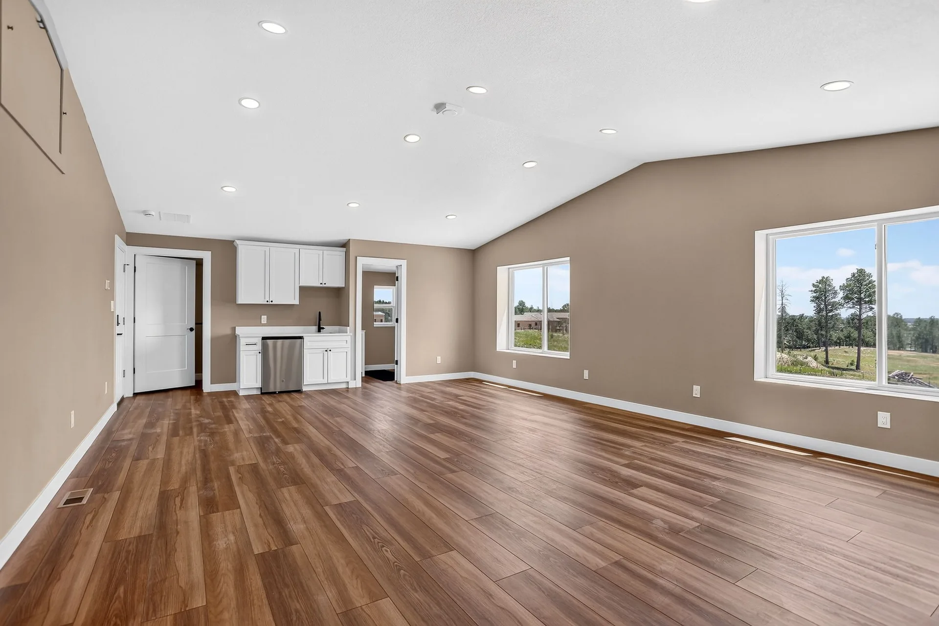 Airy loft living area with a wet bar, vaulted ceiling, and large windows above the shop