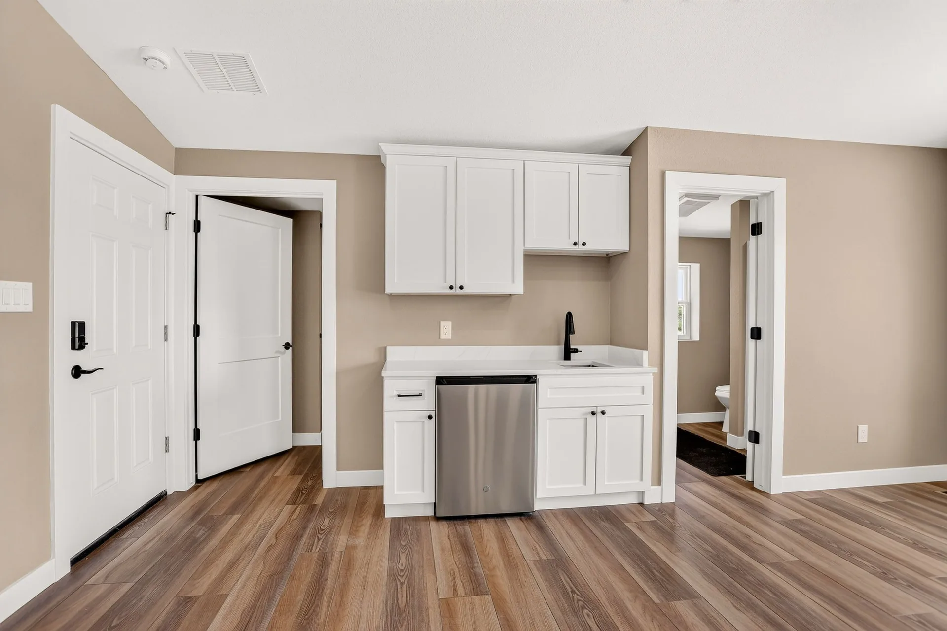 Wet bar kitchenette with white cabinets and beverage fridge