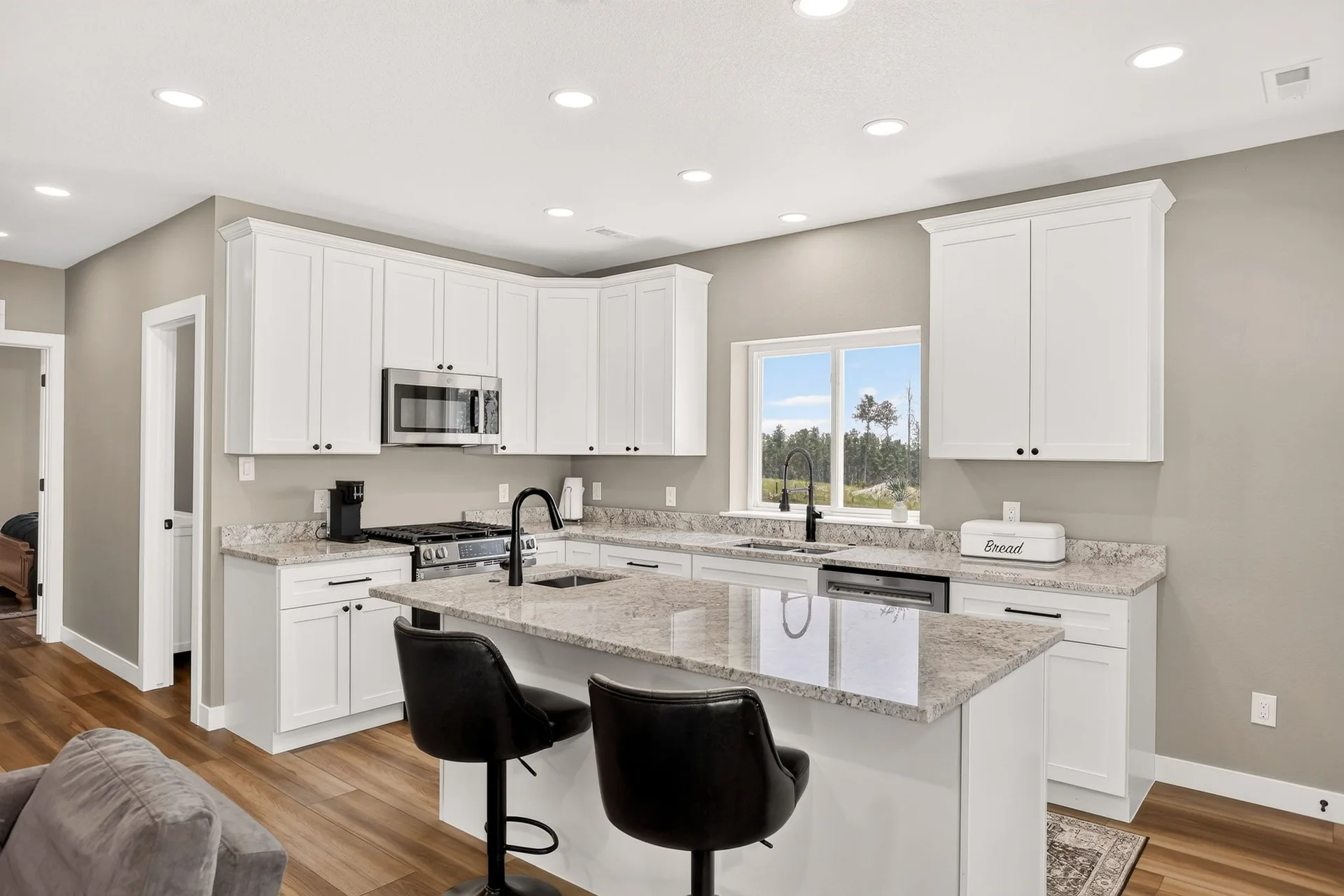 Modern lower-level kitchen with white shaker cabinets and granite countertops