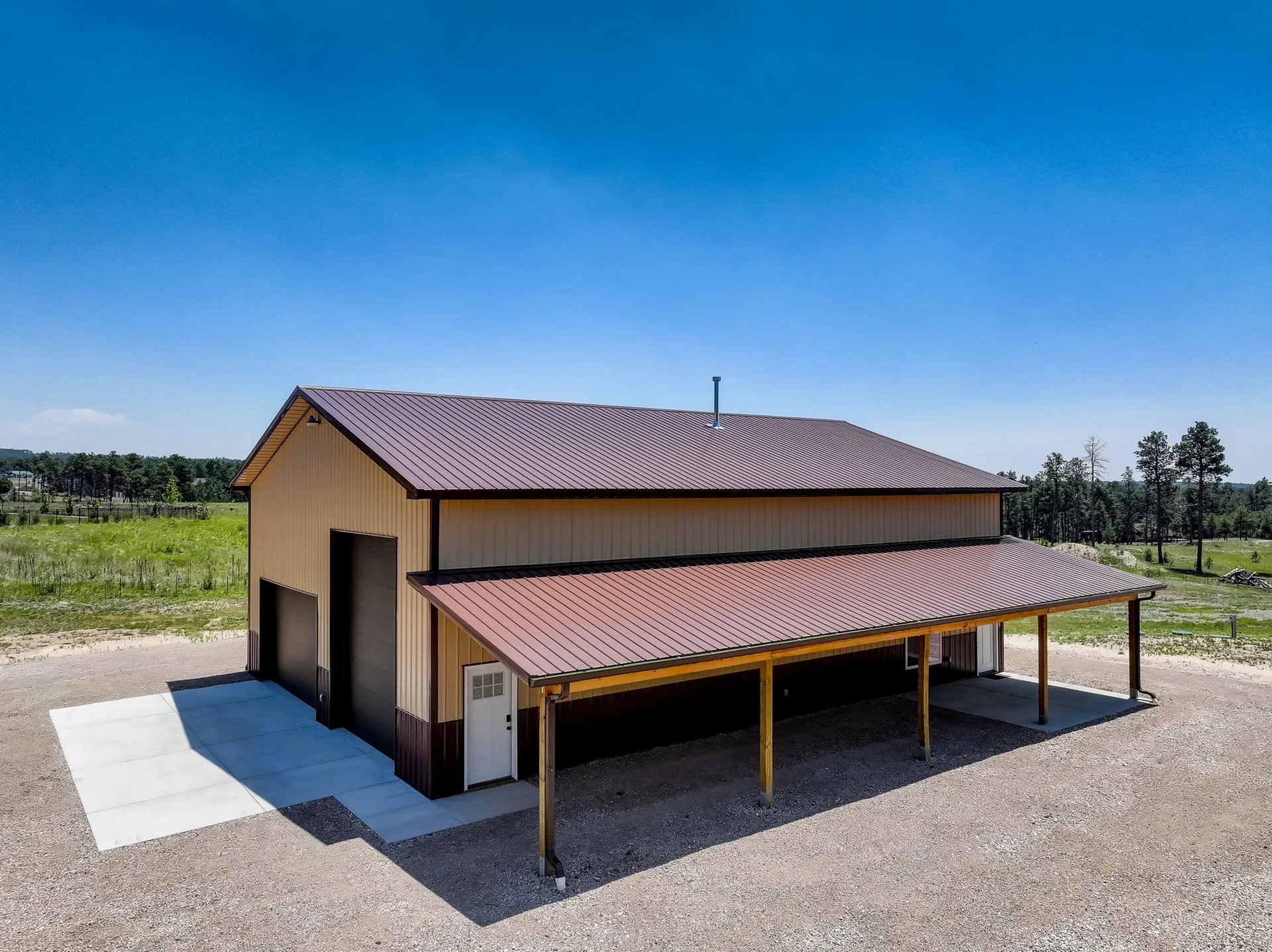 Exterior of the brand-new shop building with two-tone metal siding, overhead doors, and a covered side porch
