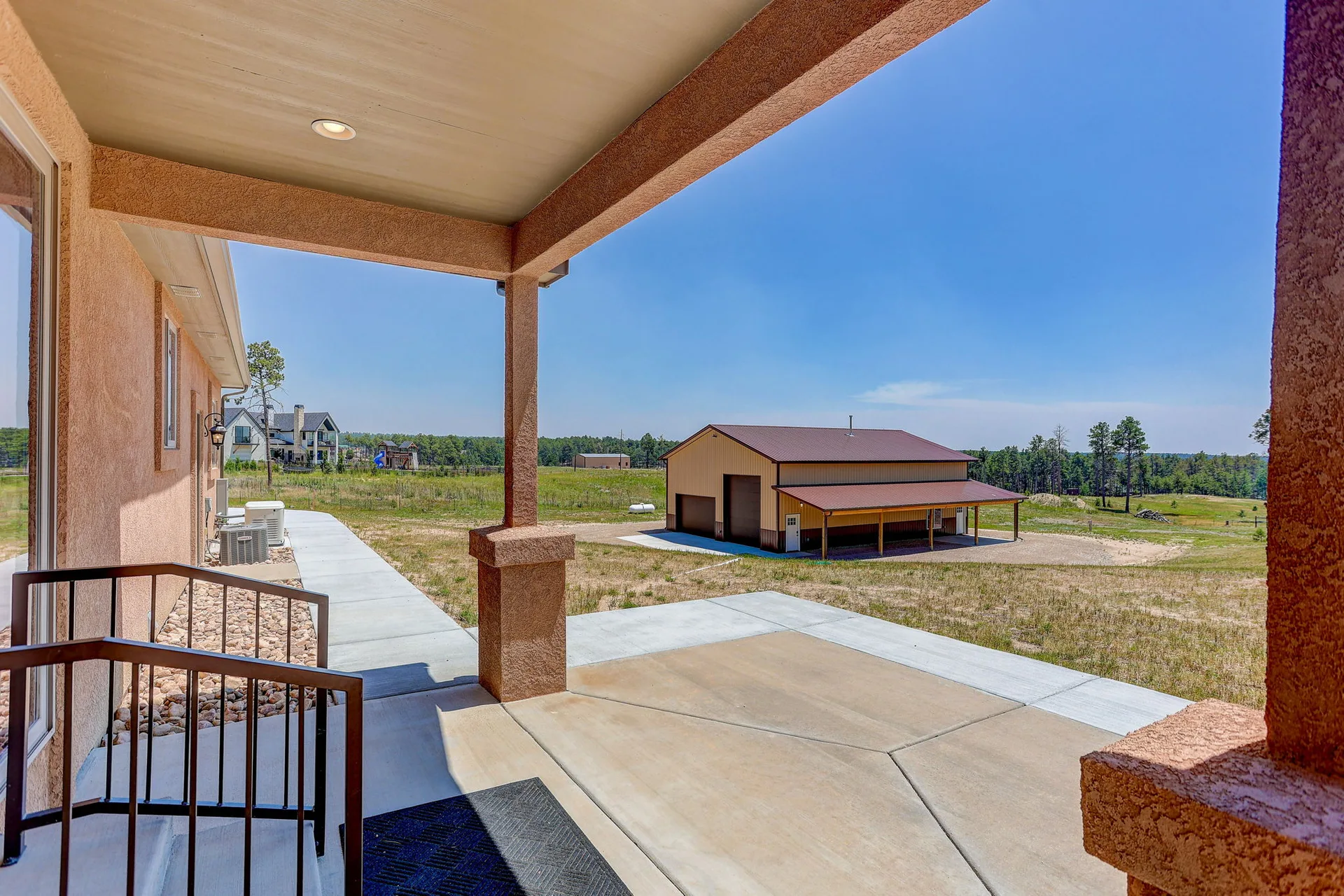 Backyard patio view toward detached workshop with pine trees