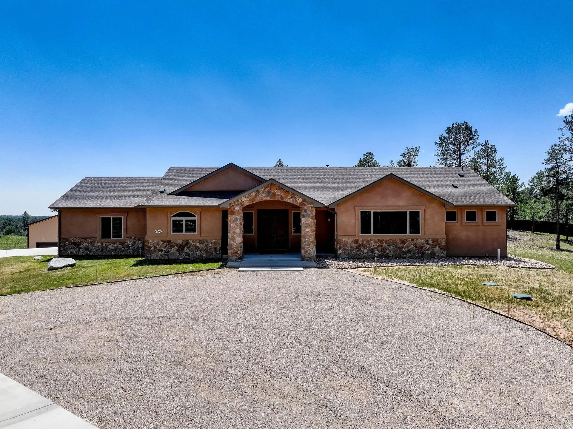 Front view of ranch home with tan stucco and stone veneer