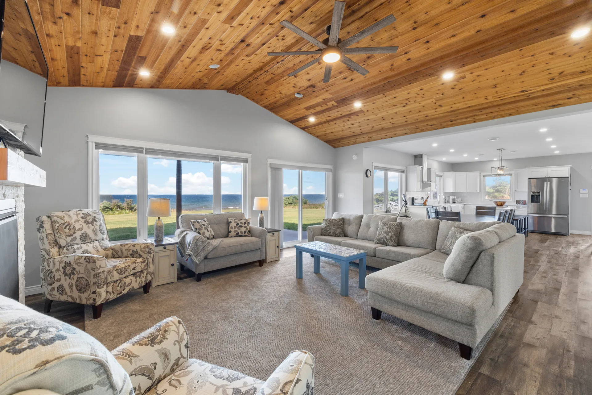 Open-concept living area with vaulted wood ceilings and ocean views