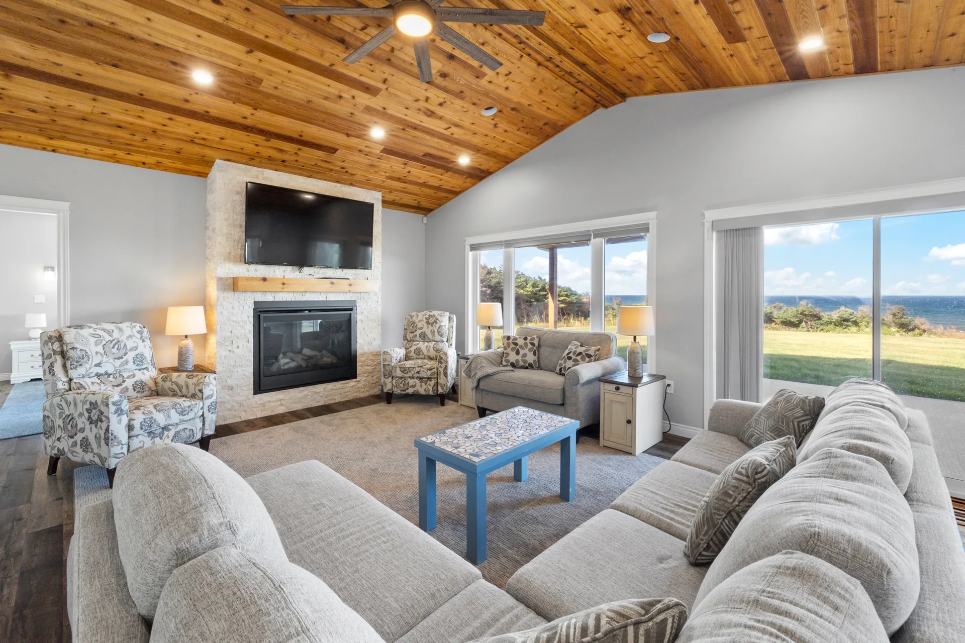 Living room with vaulted wood-plank ceilings and stone fireplace