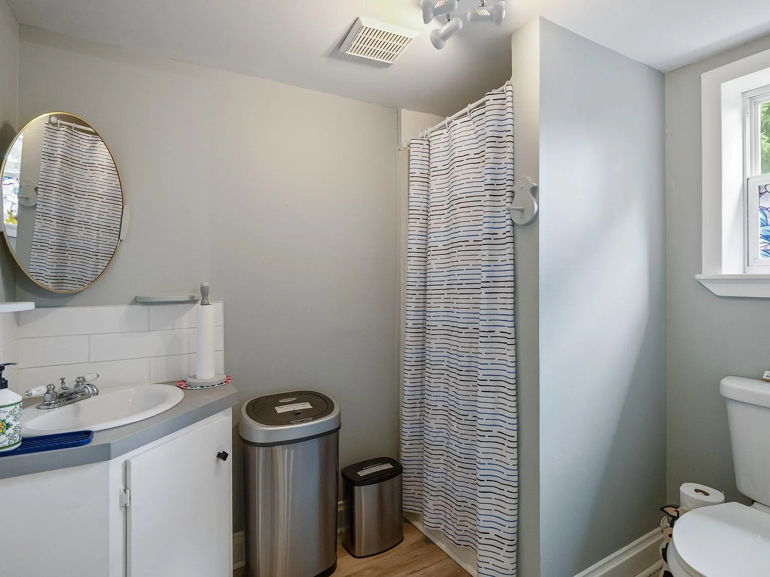 Updated bathroom with white vanity, grey countertop, and tiled backsplash