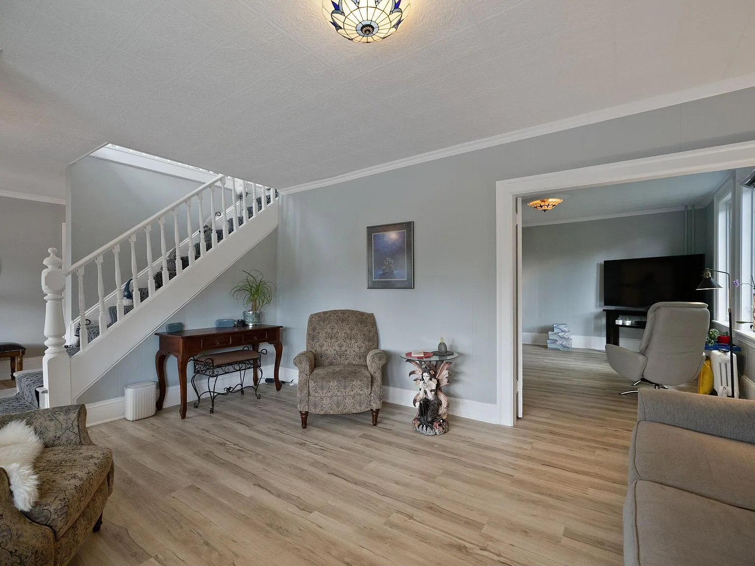 Living room showcasing main seating area and stairwell with crown moulding