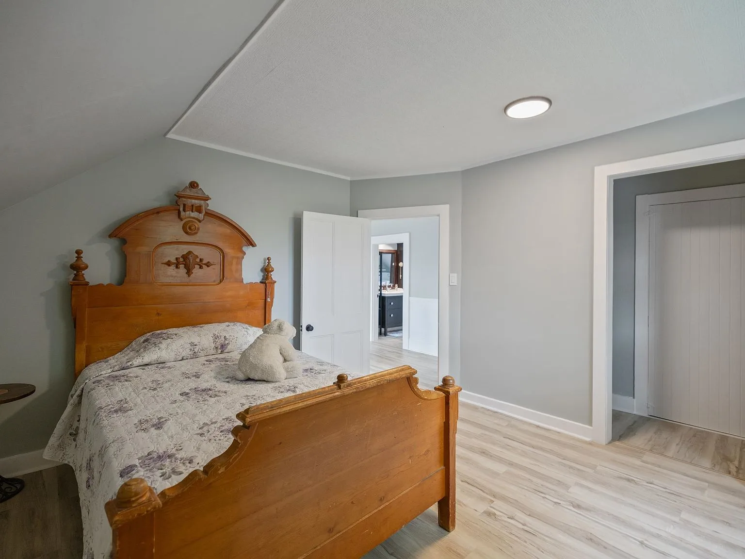 Renovated bedroom with light grey walls and wood-tone flooring
