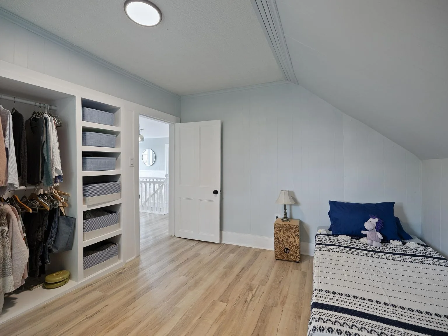 Bedroom with light blue walls, sloped ceiling, and built-in shelving