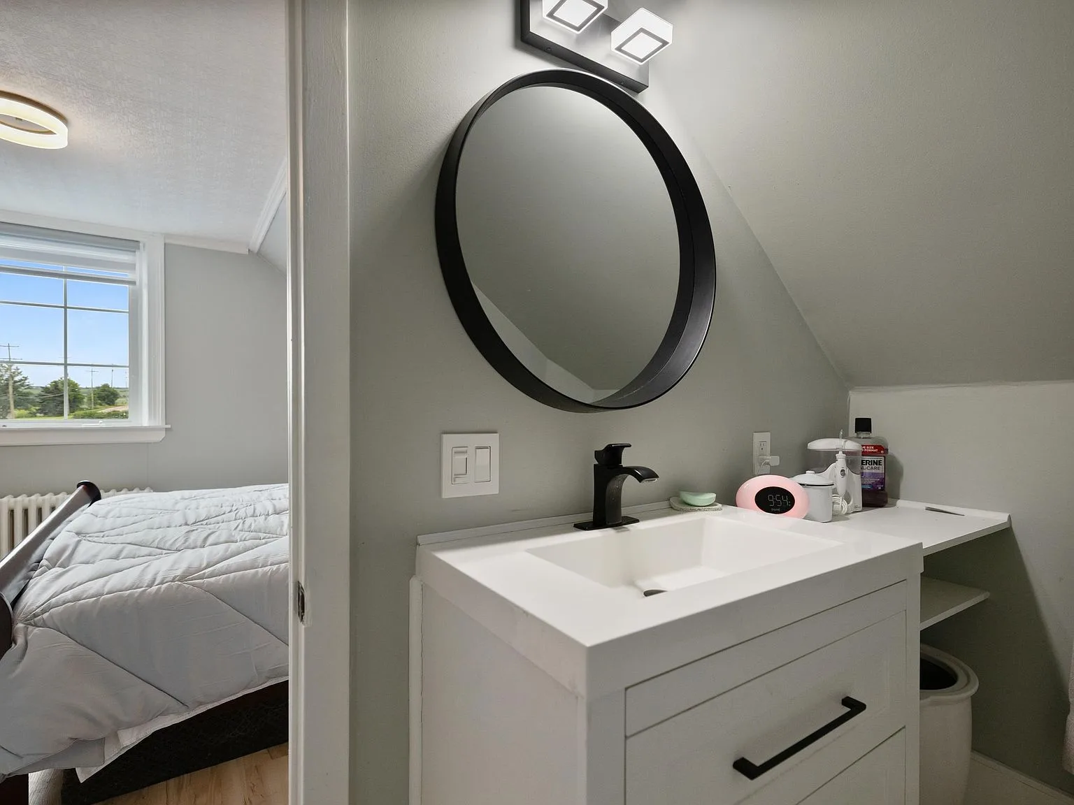 Bathroom vanity with matte black circular mirror and white vanity