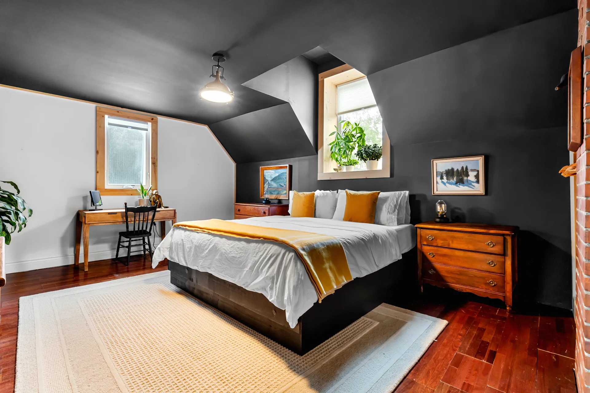 Loft-style master bedroom with slanted ceilings, exposed brick accent, and warm wood trim