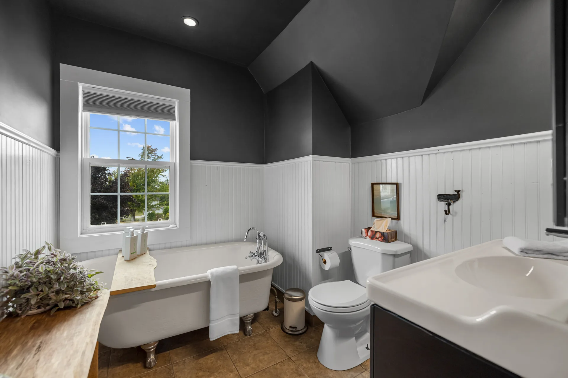 Classic bathroom with dark grey walls, white wainscoting, and clawfoot tub