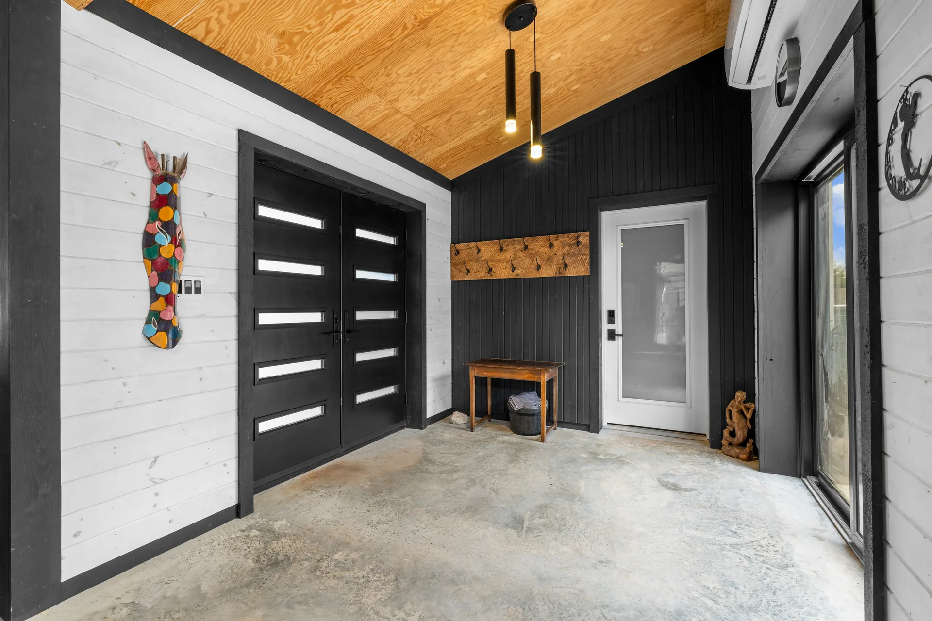 Modern farmhouse entryway with white shiplap walls, black trim accents, and polished concrete flooring