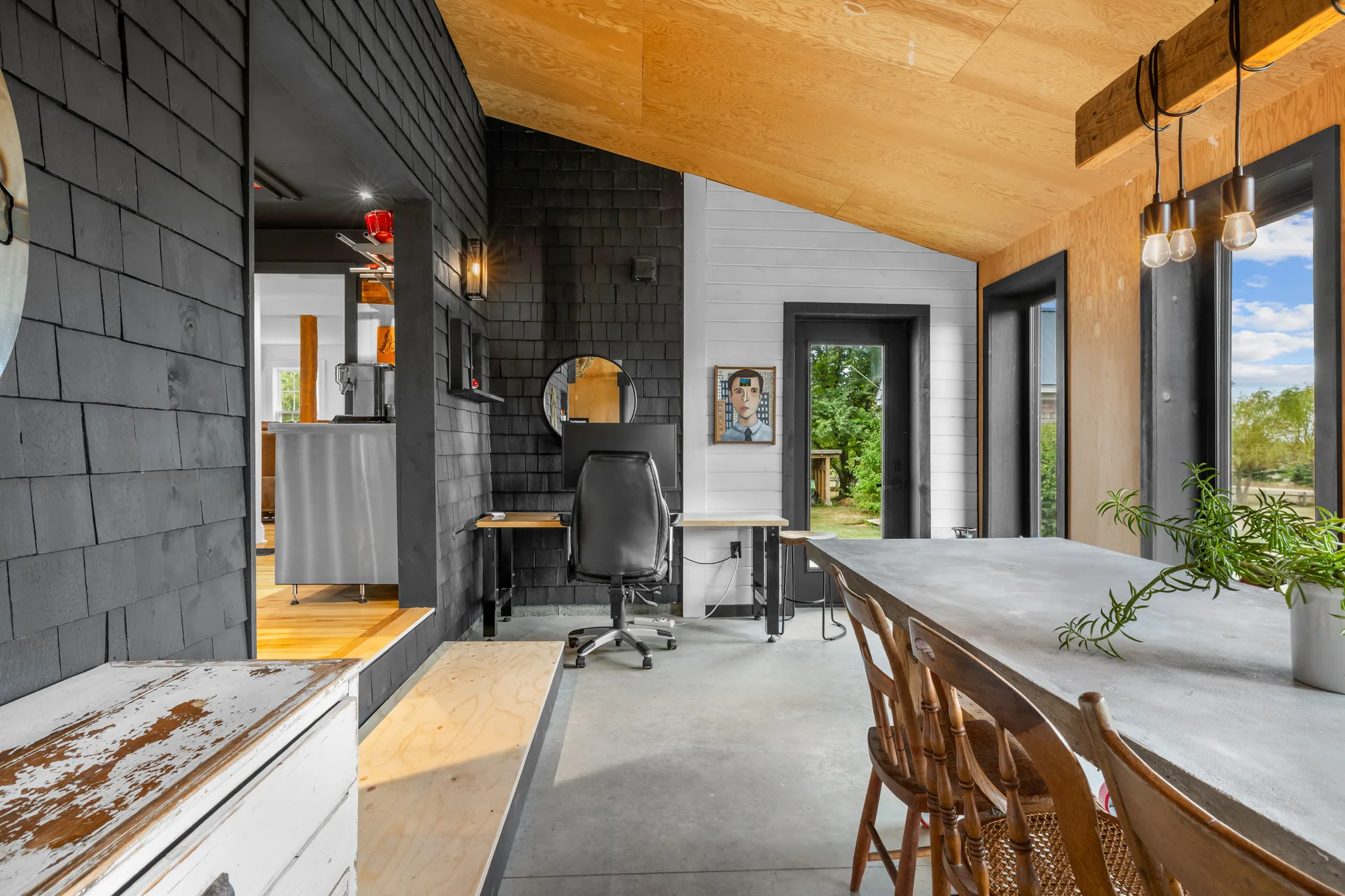 Multi-purpose sunroom space with black cedar shingles, white tongue-and-groove walls, and concrete flooring