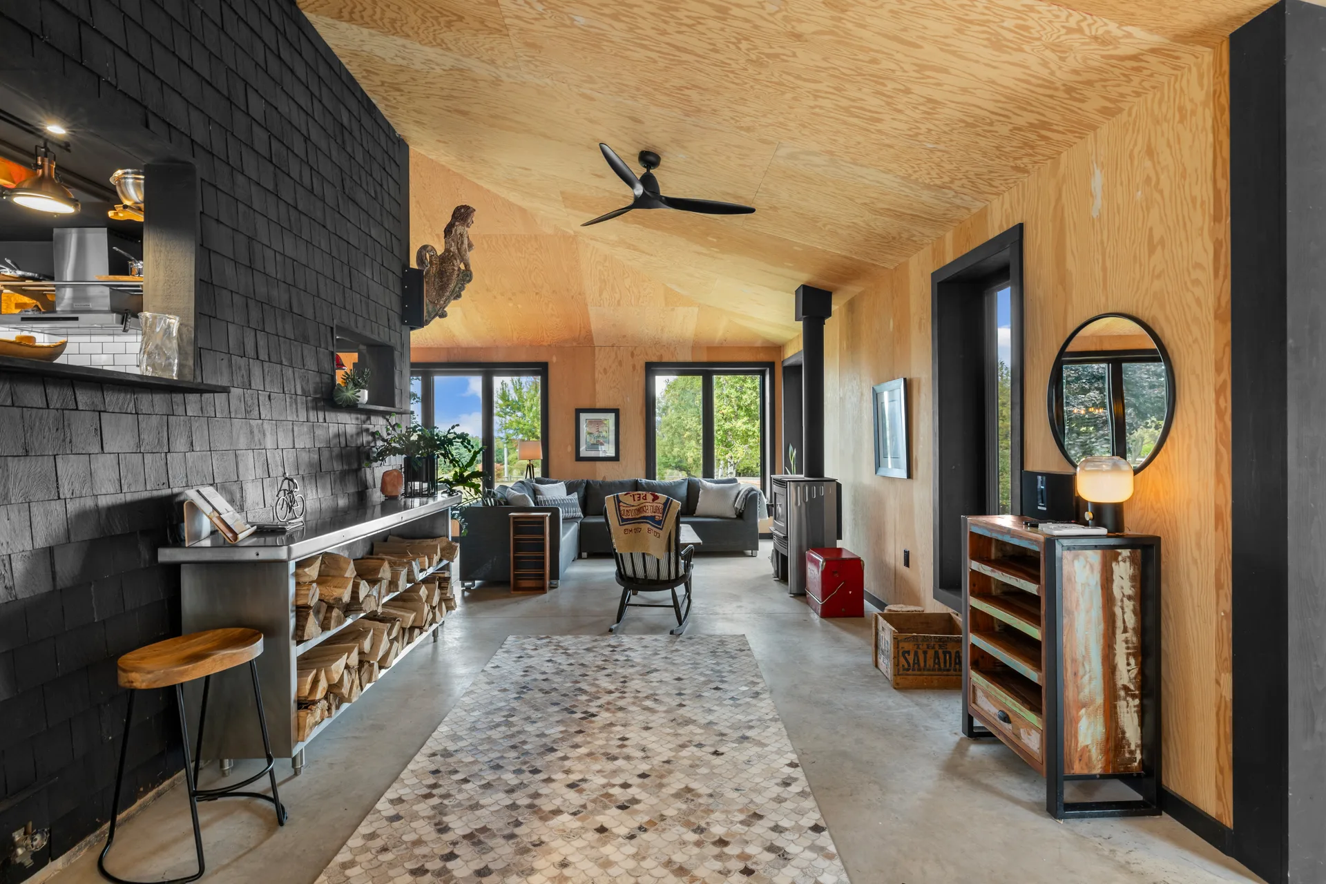 Open-concept living area in the barn-inspired addition with black shingle feature wall and concrete floors